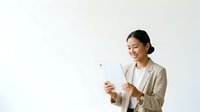 Young Asian woman in business casual attire holding and viewing digital tablet against neutral background, suitable for corporate, technology, and professional business applications.