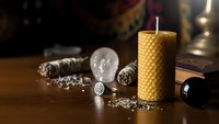 Handcrafted beeswax candle with natural honeycomb texture surrounded by vintage metalworking tools and decorative elements on wooden surface for artisan crafts.
