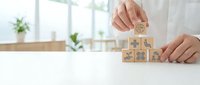 Business professional building wooden blocks with icons representing growth strategy and development concepts on modern office desk.