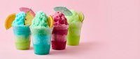 Colorful shaved ice drinks with fruit slices on pink background, perfect for summer beverage, refreshment, and frozen dessert designs.