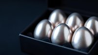 Silver metallic eggs arranged in black box against dark background, dramatic lighting creates luxurious modern minimalist composition for business and finance concepts.