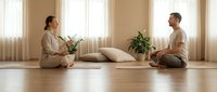 Young diverse couple practicing mindfulness meditation together in bright minimalist living room with plants and natural light streaming through windows.