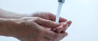 Clean fresh water flowing into cupped hands for drinking, washing, hygiene and health concept with splashing droplets against white background.