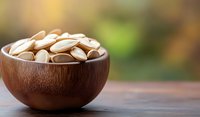 Roasted pumpkin seeds in wooden bowl on rustic table with blurred natural background, healthy snack rich in nutrients and minerals.