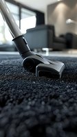 Modern vacuum cleaner brush head on dark carpet, close-up view with selective focus showing cleaning technology in action. Suitable for household and cleaning service ads.
