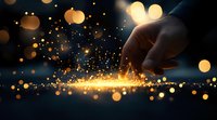 Magical glowing sparkles and golden light particles scatter from finger touch against dark background, creating ethereal bokeh effect and mystical atmosphere.