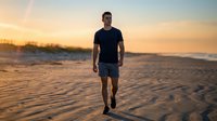 Athletic man jogging on sandy beach at sunset, wearing black shirt and shorts. Fitness and outdoor exercise concept for wellness and healthy lifestyle campaigns.