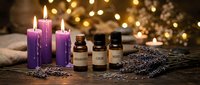 Aromatherapy essential oil bottles with purple candles and lavender sprigs creating relaxing spa atmosphere with warm bokeh lights for wellness treatments.