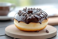 Fresh baked donut with dark chocolate glaze and mini chocolate chips on wooden serving board, selective focus on sweet dessert pastry.