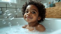 Joyful African American toddler playing with soap bubbles during bath time, natural curly hair, genuine smile, warm lighting creates cozy bathroom atmosphere.