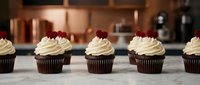 Row of chocolate cupcakes with vanilla frosting and red velvet hearts on marble counter in modern kitchen for bakery display and dessert marketing.