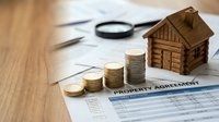 Property investment concept with wooden house model, coin stacks and magnifying glass on contract documents for real estate planning and mortgage analysis.