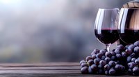 Two glasses of red wine and fresh dark grapes on rustic wooden table with soft blurred background, romantic evening atmosphere for wine tasting or date night.