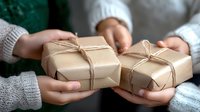Hands in cozy white sweaters holding kraft paper wrapped presents with twine bows. Exchanging gifts during winter holiday season creates warm festive atmosphere.