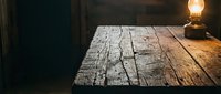 Rustic wooden table surface illuminated by warm vintage lamp in dark interior space, suitable for product placement and lifestyle photography.
