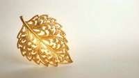 Golden ornate leaf with intricate filigree pattern isolated on white background for luxury design projects and decorative applications.