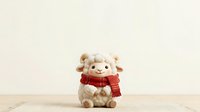 Cute stuffed lamb toy wearing red knitted scarf sitting on wooden surface against neutral beige background, suitable for holiday greeting cards and seasonal marketing materials.