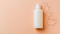 White cosmetic bottle on peach colored background with cracked texture pattern, minimalist beauty product mockup for skincare and personal care branding.