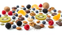 Assorted healthy snacks including fresh berries, nuts, chocolate pieces and kiwi slices scattered on white background for nutritious eating concepts.