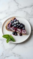 Slice of blueberry cheesecake on white plate with fresh berries and mint garnish on marble surface for bakery menu or dessert photography.