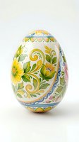 Hand-painted ceramic Easter egg with colorful floral folk art patterns featuring yellow flowers and green leaves on white background isolated.