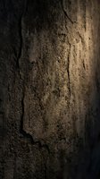 Dark cracked stone wall texture with dramatic lighting, rough grunge surface background for design, wallpaper, or web projects.