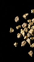 Raw gold nuggets scattered on black background with copy space for mining industry and precious metals investment concepts.