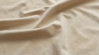 Soft beige fabric with natural wrinkles and folds creating elegant textile background for fashion and interior design projects.