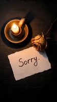Handwritten sorry note on torn paper beside a dried rose and glowing candle on dark slate, evoking apology, regret, and reconciliation.