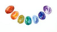 Colorful gemstones arranged in rainbow gradient from red to purple on white background, isolated faceted crystals for design, jewelry, and decorative projects.