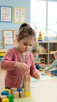 Young girl building wooden block tower in bright preschool classroom with educational posters and toys, developing fine motor skills and creativity.
