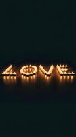 Glowing tealight candles arranged to spell LOVE on a dark wooden floor, creating a warm romantic atmosphere for Valentine's Day.