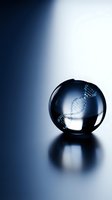 DNA double helix structure inside transparent glass sphere on reflective surface with dramatic blue lighting for genetics and biotechnology concepts.