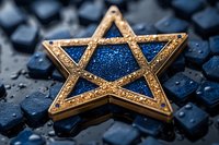 Golden Star of David with blue glittery center on dark wet surface, symbolic Jewish religious emblem representing faith and heritage.