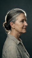 Elegant senior Caucasian woman with gray hair in profile view, calm expression, wearing linen shirt, dark studio background, aging gracefully.