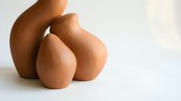 Handcrafted terracotta clay pottery vessels in warm earth tones arranged on white surface for modern home decor and artisan craft projects.