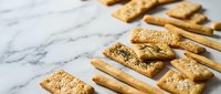 Assorted crackers with sesame seeds arranged on marble surface for food styling, baking, culinary, and recipe content.