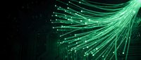 Green fiber optic cables with glowing light streams on dark background for technology and communication network concepts.