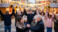 Joyful multigenerational diverse family celebrating together at a festive Christmas market with glowing lights and holiday stalls in the background.