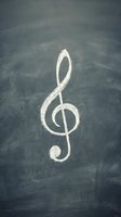 White chalk treble clef symbol drawn on dark chalkboard surface for music education and classroom teaching concepts.