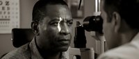 African American man receiving comprehensive eye examination from optometrist using advanced diagnostic equipment in modern clinic setting.