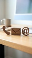 Wooden contact icons on office desk representing phone, email and web communication for business customer service and support concepts.