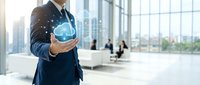 Professional businessman holding glowing cloud computing icon in modern office environment with digital network connections and data transfer concept.