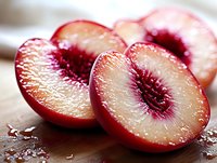 Sliced red plums with pits exposed, displaying juicy flesh and vibrant interior colors on wooden surface. Use for food photography, culinary content, healthy eating, and recipe design.