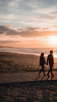 Romantic couple walking hand in hand on beach at sunset with golden sky and ocean waves creating peaceful evening atmosphere for love and relationship concepts.