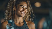 Happy mixed race woman with curly hair smiling during workout at gym. Fitness lifestyle and healthy living concept for wellness and exercise motivation.