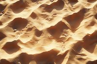 Golden sand dunes create abstract natural patterns with deep shadows and rippling textures in desert landscape, aerial perspective shows wind-carved formations.