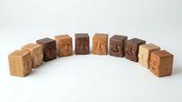 Carved wooden blocks with expressive human faces arranged in a semicircle, showcasing diverse skin tones and emotions on a white background.