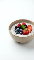 Chia seed pudding topped with fresh berries and mint in ceramic bowl on white background for healthy breakfast recipes and superfood content.
