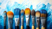 Professional makeup brushes arranged in row against artistic blue paint strokes background, showcasing beauty tools and creative cosmetic application equipment.